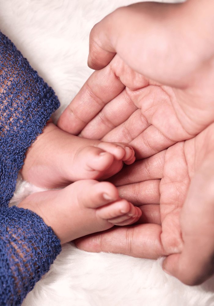 Petits pieds de bébé dans les mains de son papa